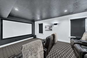 Home theater room featuring a textured ceiling, dark colored carpet, and recessed lighting