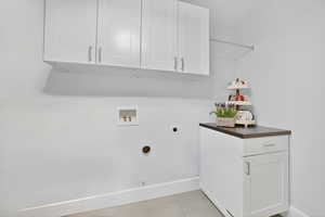 Laundry room with cabinet space, washer hookup, hookup for an electric dryer, light tile patterned floors, and hookup for a gas dryer