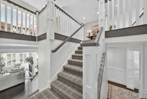 Staircase with wood finished floors, a high ceiling, and recessed lighting