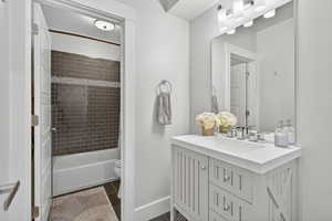 Full bathroom featuring vanity, dark tile patterned floors, and  shower combination