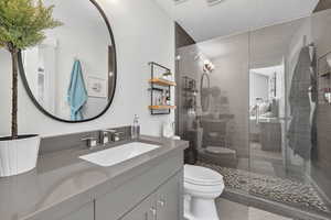 Full bath featuring vanity, a textured ceiling, tiled shower, and light tile patterned flooring