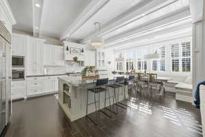 Kitchen featuring pendant lighting, open shelves, a breakfast bar, a center island, and tasteful backsplash