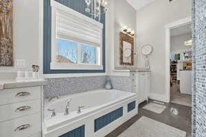 Primary Bathroom featuring vanity, a bath, dark tile patterned flooring, and a chandelier