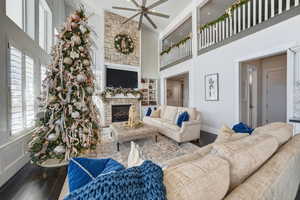 Living area with wood finished floors, a fireplace, a high ceiling, and ceiling fan