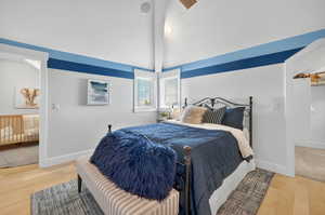 Bedroom with a textured ceiling, vaulted ceiling, and light wood-type flooring