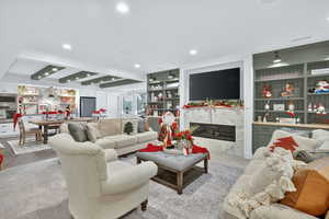 Living area with beam ceiling, built in shelves, a high end fireplace, recessed lighting, and wood finished floors