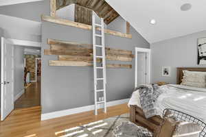 Bedroom with wood finished floors, high vaulted ceiling, and recessed lighting