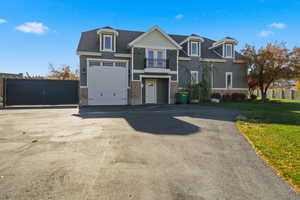 View of front of house featuring a balcony, driveway, and stone siding