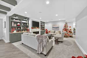 Living room with a glass covered fireplace, recessed lighting, and built in features