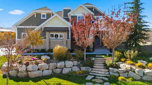 Craftsman house featuring a standing seam roof, stone siding, board and batten siding, a metal roof, and a front yard