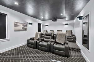 Cinema room with a textured ceiling, dark carpet, and recessed lighting