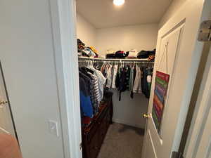 Walk in closet with dark colored carpet