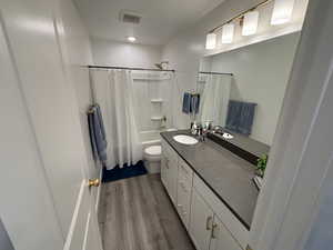 Bathroom featuring vanity, dark wood-style flooring, and shower / bath combo with shower curtain