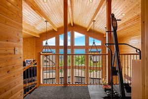 Workout room featuring wood walls, a chandelier, a wood ceiling with exposed beams, carpet, and high vaulted ceiling