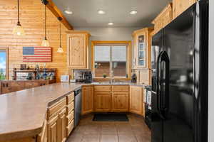Kitchen with black appliances, hanging light fixtures, recessed lighting, a peninsula, and glass insert cabinets