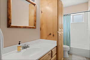 Bathroom featuring vanity, shower / bath combination with curtain, and light tile patterned floors