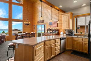 Kitchen with wooden walls, a water view, pendant lighting, a peninsula, and dishwasher