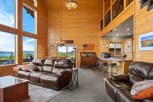 Carpeted living room featuring wooden walls, plenty of natural light, a high ceiling, a chandelier, and a mountain view