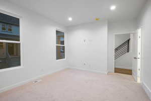 Unfurnished room featuring stairs, light colored carpet, and recessed lighting