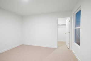 Unfurnished bedroom with a walk in closet and light carpet