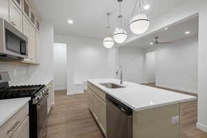 Kitchen with appliances with stainless steel finishes, dark wood finished floors, recessed lighting, ceiling fan, and a kitchen island with sink