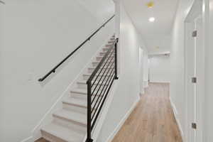 Staircase featuring wood finished floors and recessed lighting