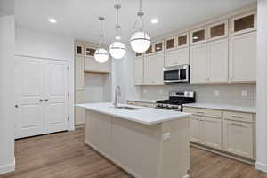 Kitchen featuring appliances with stainless steel finishes, pendant lighting, backsplash, glass insert cabinets, and recessed lighting