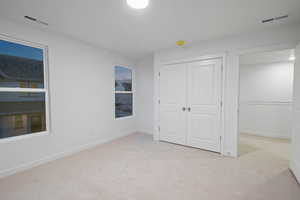 Unfurnished bedroom with light carpet and a closet