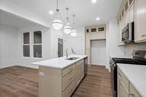 Kitchen featuring stainless steel appliances, cream cabinets, glass insert cabinets, dark wood-type flooring, and recessed lighting