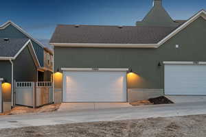 View of front of home featuring a shingled roof, driveway, and stucco siding