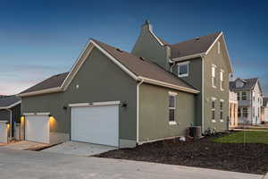 View of side of home with stucco siding, concrete driveway, an attached garage, roof with shingles, and a chimney