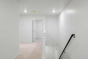 Corridor featuring light colored carpet, an upstairs landing, and recessed lighting