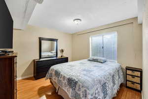 Bedroom with light wood-style floors, a textured ceiling, and a textured wall