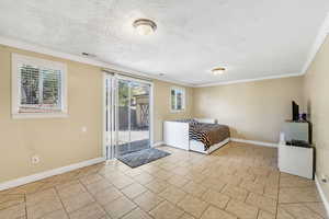 Unfurnished bedroom with crown molding, access to exterior, light tile patterned flooring, and a textured ceiling