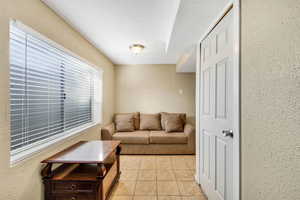 Living room with a textured wall, light tile patterned floors, and a textured ceiling