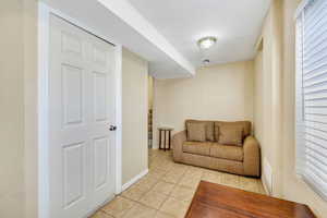 Sitting room featuring light tile patterned floors, healthy amount of natural light, stairs, and a textured ceiling