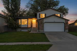 Split level home with driveway and brick siding