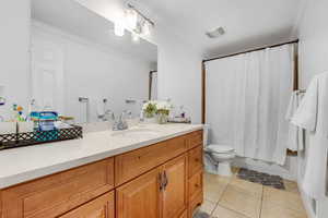 Bathroom with vanity, light tile patterned floors, crown molding, and shower / tub combo