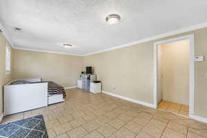 Bedroom with ornamental molding, a textured ceiling, and light tile patterned floors