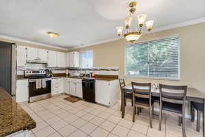 Kitchen featuring stainless steel appliances, ornamental molding, tasteful backsplash, white cabinets, and light tile patterned flooring
