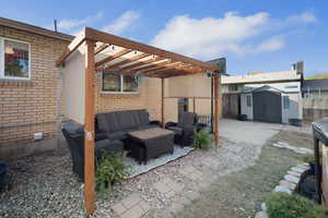 Fenced backyard featuring a patio area, outdoor lounge area, a storage shed, and a pergola