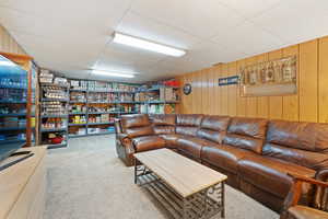 Living area featuring a drop ceiling, wooden walls, and light carpet