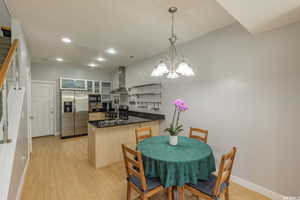 Kitchen featuring a peninsula, glass insert cabinets, stainless steel appliances, light wood-type flooring, and recessed lighting