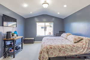 Carpeted bedroom with vaulted ceiling and recessed lighting