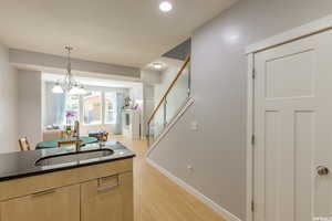 Kitchen featuring dark stone counters, light brown cabinetry, light wood-style floors, pendant lighting, and recessed lighting