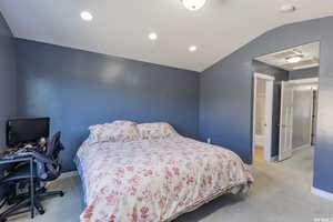 Carpeted bedroom featuring vaulted ceiling, recessed lighting, connected bathroom, and an office area