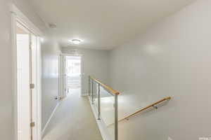 Hall with an upstairs landing and light colored carpet