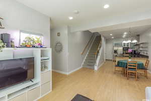 Living room with stairway, recessed lighting, light wood finished floors, and a chandelier