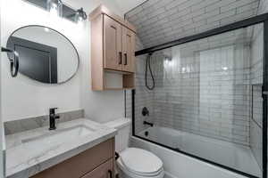 Bathroom with bath / shower combo with glass door and vanity