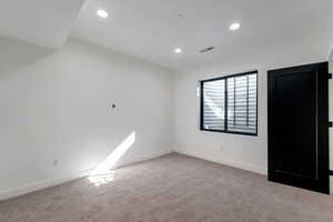 Empty room with light carpet and recessed lighting